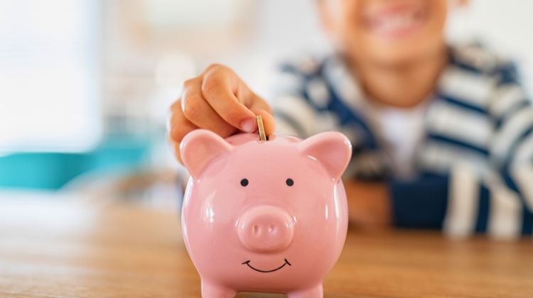 child putting a coin into a piggy bank