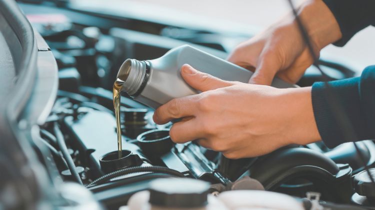 person adding motor oil to car
