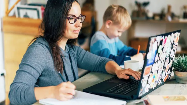 mom works at computer while child draws